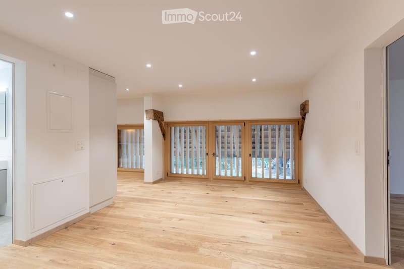 Large wooden doors, large windows, balcony, wooden floor, white walls