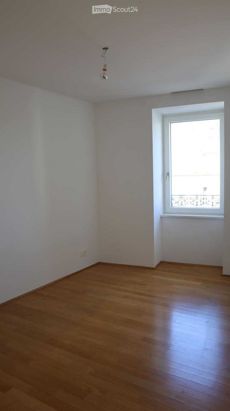 Empty room with white walls, wooden floor, and a window
