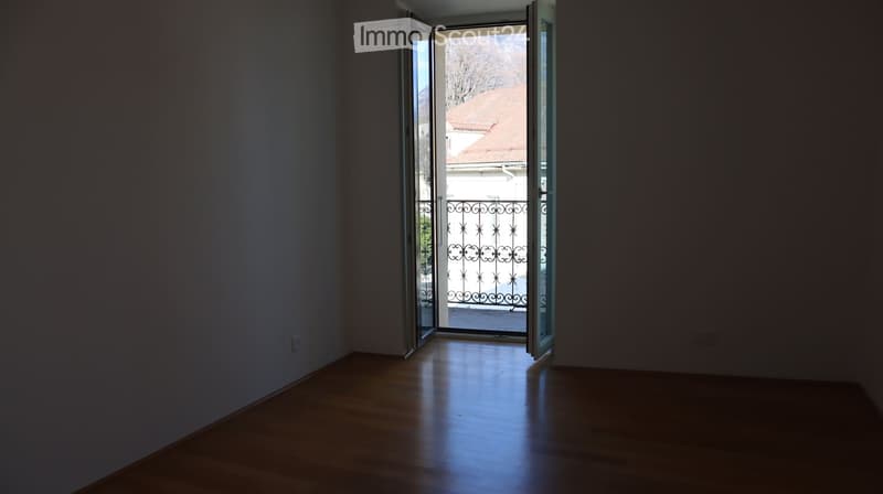 empty room, wooden floor, white walls, open door to balcony, metal railings