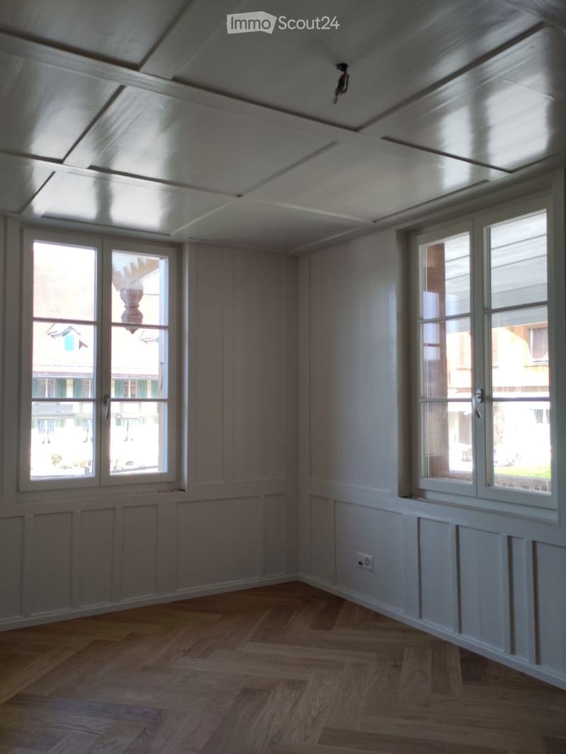 empty room, white walls, wooden floor, two windows, power outlet