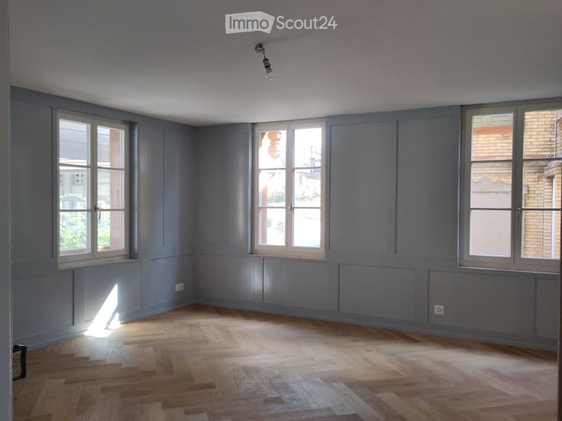 empty room, wooden floor, gray walls, three windows, ceiling light