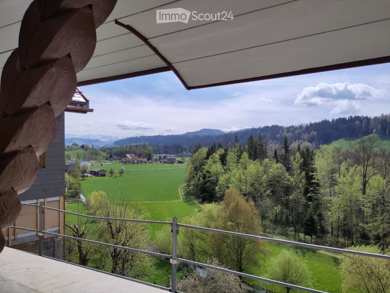 balcony with railing, view of a green field, trees, houses, mountains