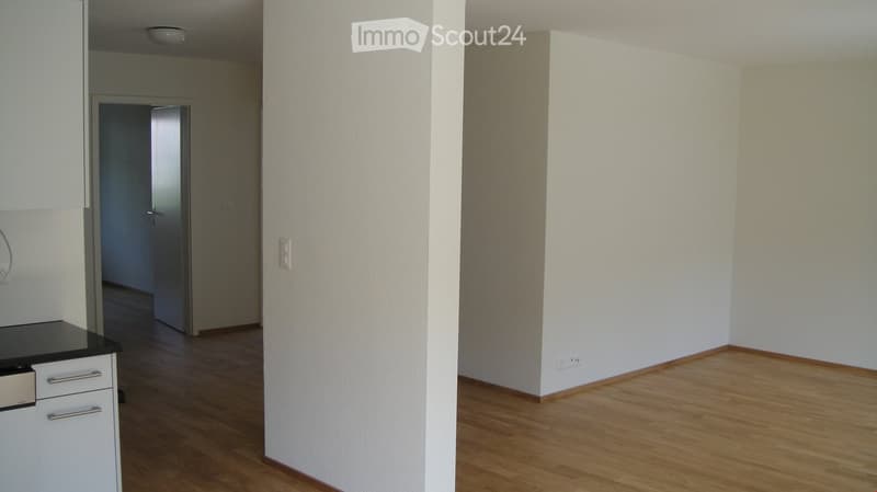 Empty room with wooden flooring, white walls, and a door leading to another room. No furniture or equipment is present.