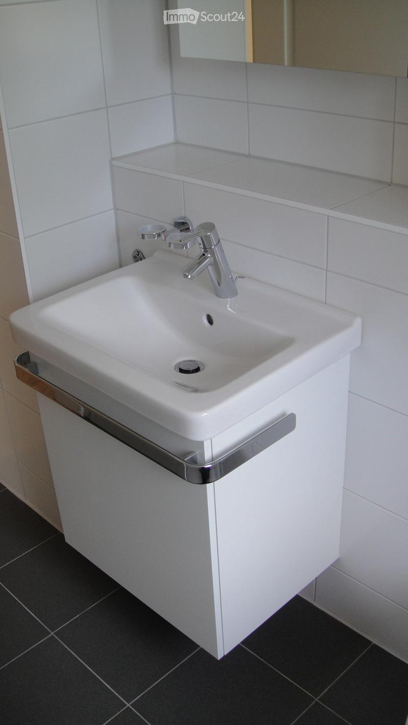 Modern bathroom sink with chrome faucet and white tiles.