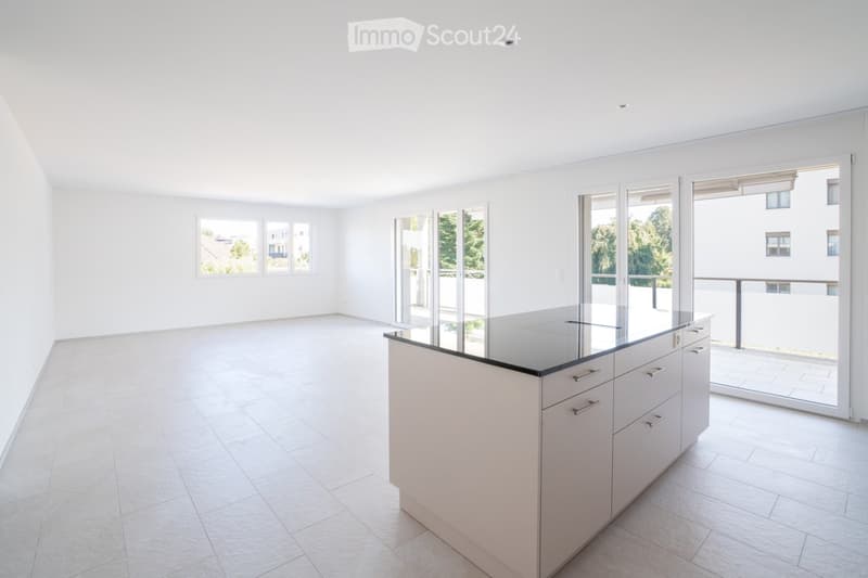 Bright, minimalist kitchen with white tiled flooring, white walls, and a central kitchen island with a black countertop and integrated drawers.