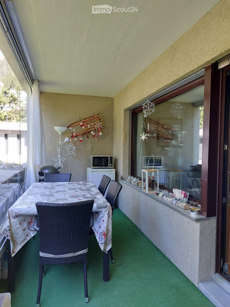 Balcony with green carpeting, a dining table with chairs, microwave, refrigerator, and decorative snowflake ornaments.