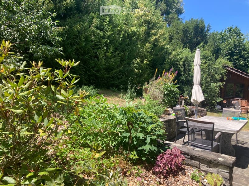 A well-maintained garden with a patio area, outdoor furniture, and lush greenery.