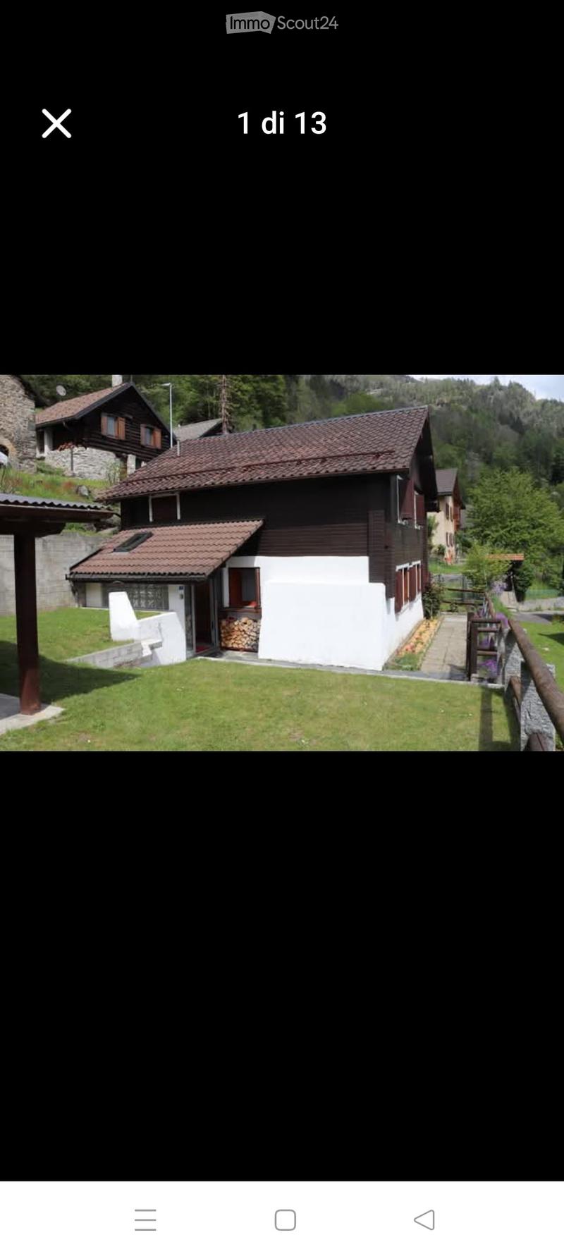A two-story house with a red-tiled roof, white and dark wooden exterior, surrounded by a well-maintained lawn and garden area.