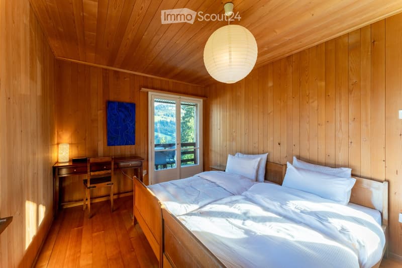 wooden interior, bed with white sheets, wooden desk, blue picture, glass window, balcony
