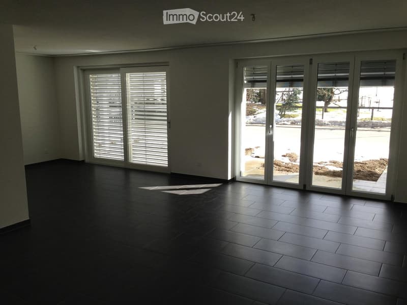 Empty room with dark tiled flooring and large sliding glass doors leading to an outdoor area.
