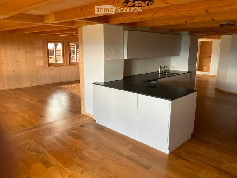 Modern kitchen with white cabinets, black countertop, and wooden flooring. Features a sink with a modern faucet and ample cabinet space.