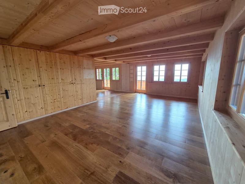 Empty room with wooden walls, wooden floor, and large windows allowing natural light. No furniture or equipment present.