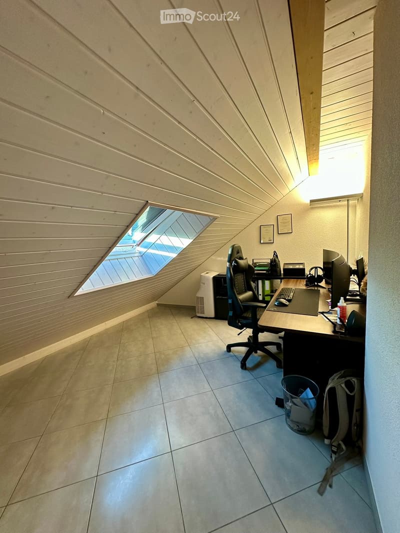 Office space with a desk, chair, computer, and air conditioner, featuring a skylight window and tiled floor.