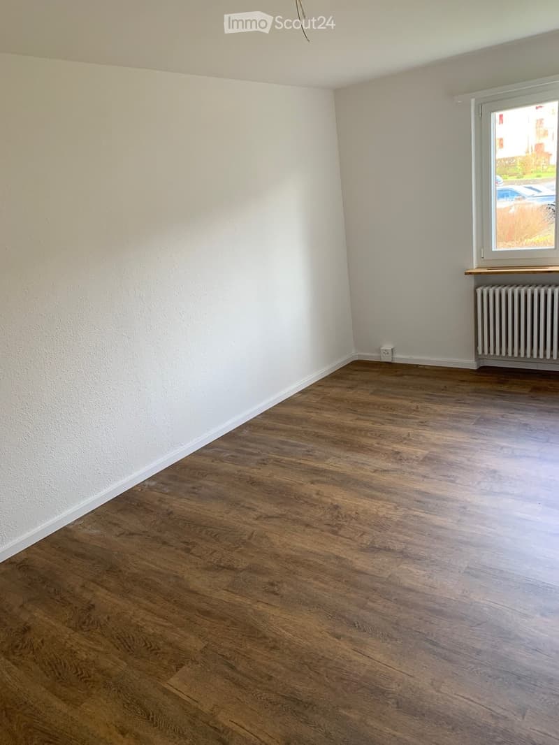 Empty room with wooden flooring and white walls, featuring a window with a radiator below it.