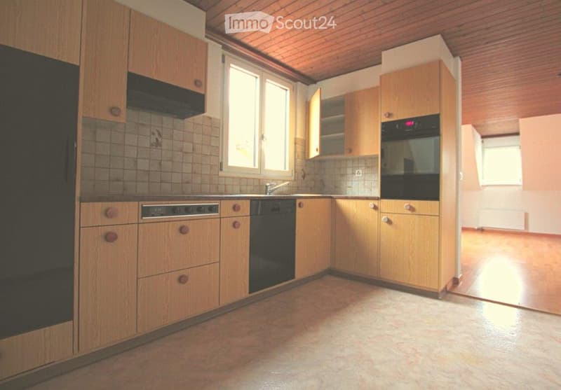 A well-lit kitchen with wooden cabinets, a sink, an oven, and a dishwasher. The space features a tiled backsplash and a wooden ceiling.