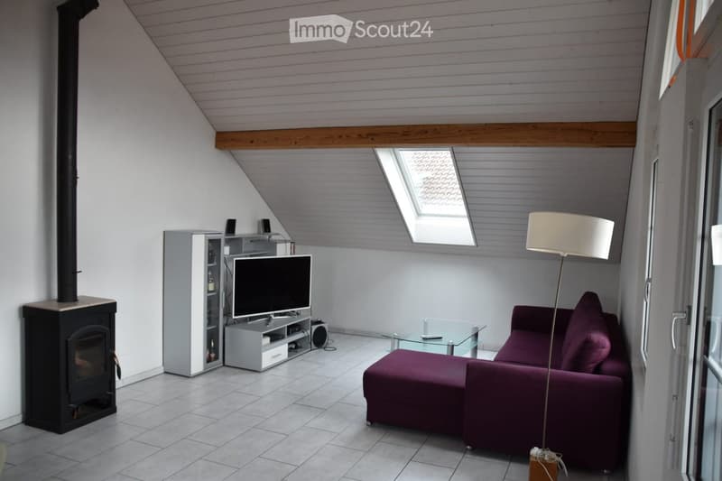 Modern living room with a slanted wooden ceiling, fireplace, purple sofa, glass coffee table, TV stand, and floor lamp.
