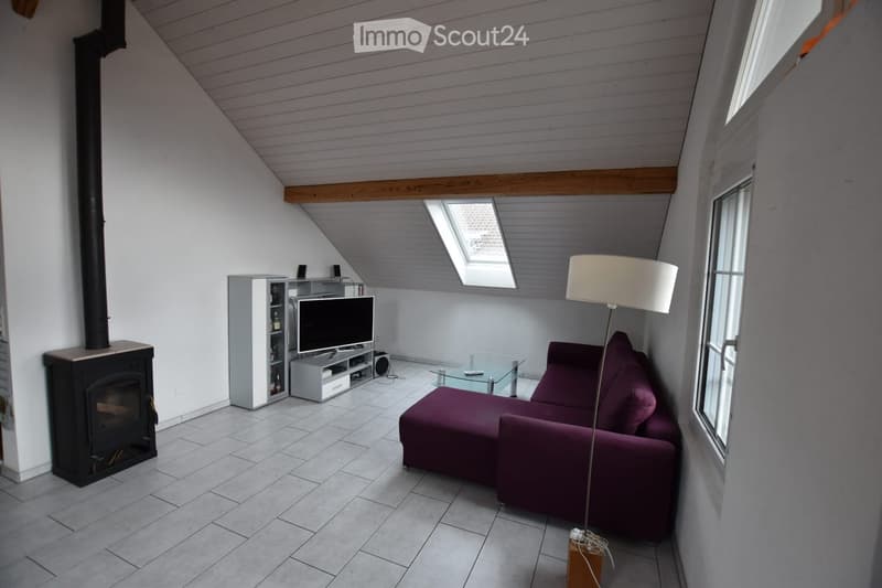 Modern living room with a slanted ceiling, fireplace, purple sofa, glass coffee table, TV, and floor lamp.