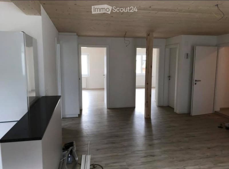 Empty room with wooden flooring, white walls, and several doors leading to other spaces. No furniture or equipment is present.