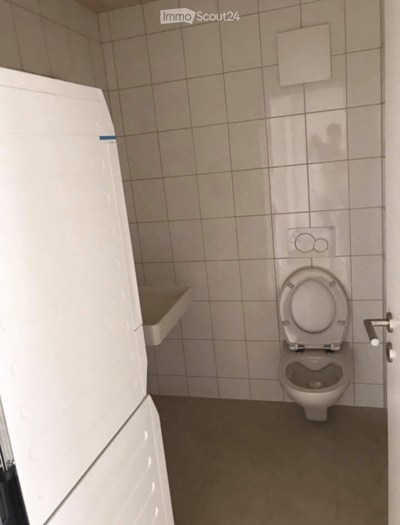 Small bathroom with a toilet and a sink, tiled walls and floor.