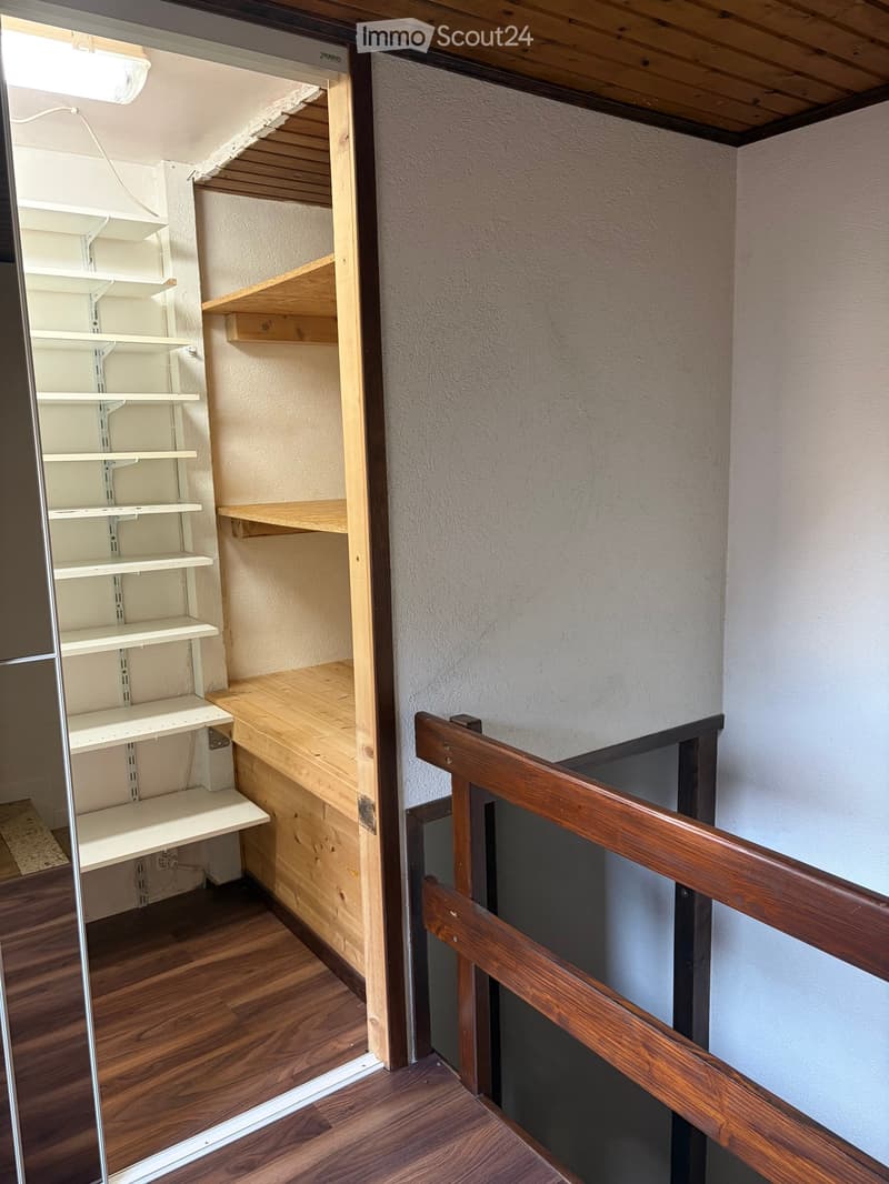 Empty hallway with wooden flooring, white walls, and built-in shelving units on one side.