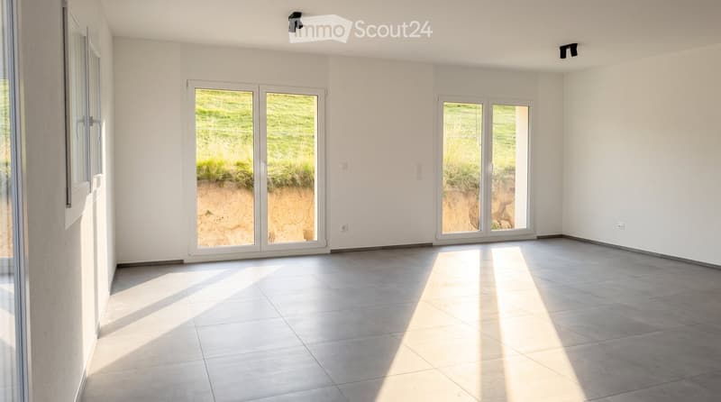 Empty room with white walls, tiled floor, and large sliding glass doors leading to an outdoor area.