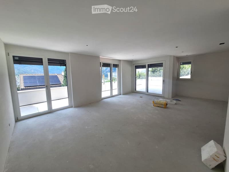 Empty room with concrete floor, white walls, large sliding glass doors, and a small window. No furniture or equipment present.