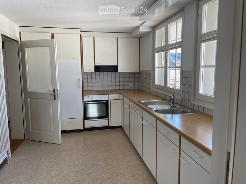Modern kitchen with white cabinets, wooden countertops, and stainless steel sink and oven.