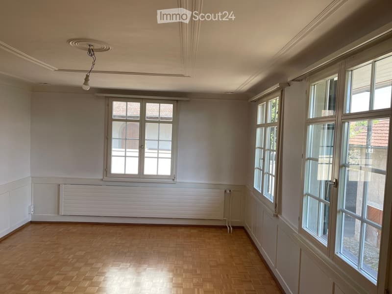 Empty room with wooden flooring, large windows, and white walls. No furniture or equipment present.