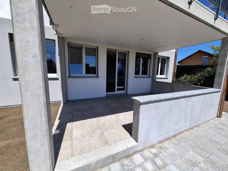 Balcony with tiled flooring, white walls, large windows, and a covered section with a railing.