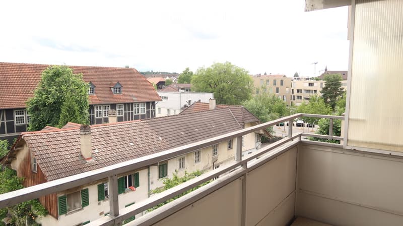 Balcony overlooking a residential area with traditional houses, trees, and a mix of modern and historic buildings.