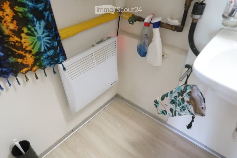 Corner bathroom, white walls, tiled floor, radiator, sink, cleaning products