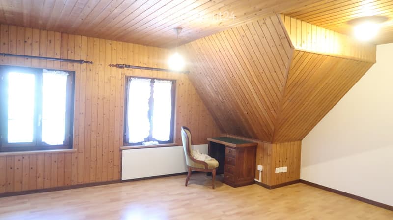 wooden walls and ceiling, 2 windows with curtains, wooden desk with drawers, and a chair