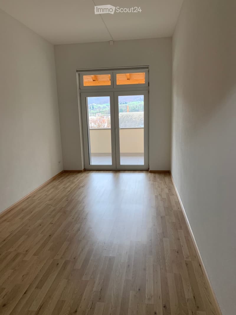 Empty room with wooden flooring and large sliding glass doors leading to a balcony or outdoor area.