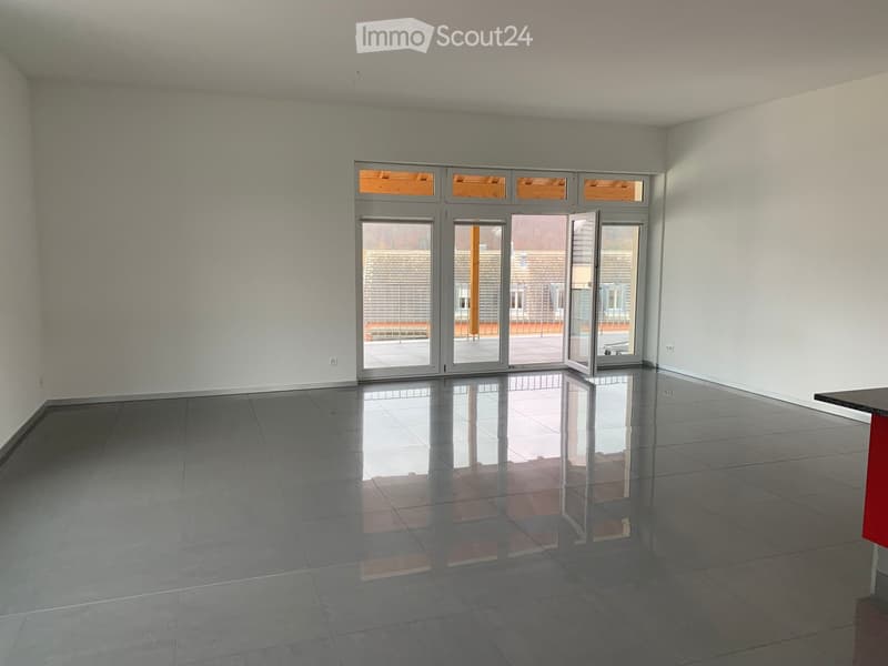 Empty room with grey tiled floor, white walls, and large glass sliding doors leading to a balcony.