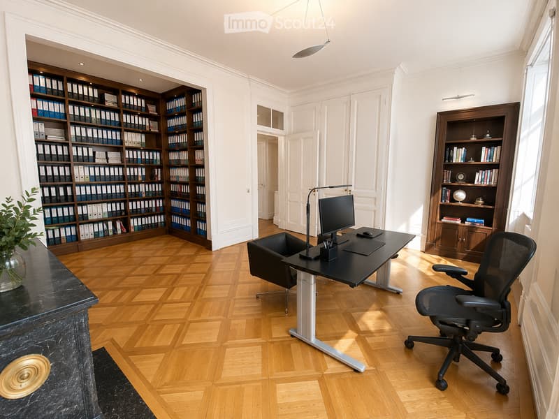 Elegant office with wooden herringbone flooring, large black desk, ergonomic chair, bookshelf filled with binders and books, and a decorative plant on a marble console.