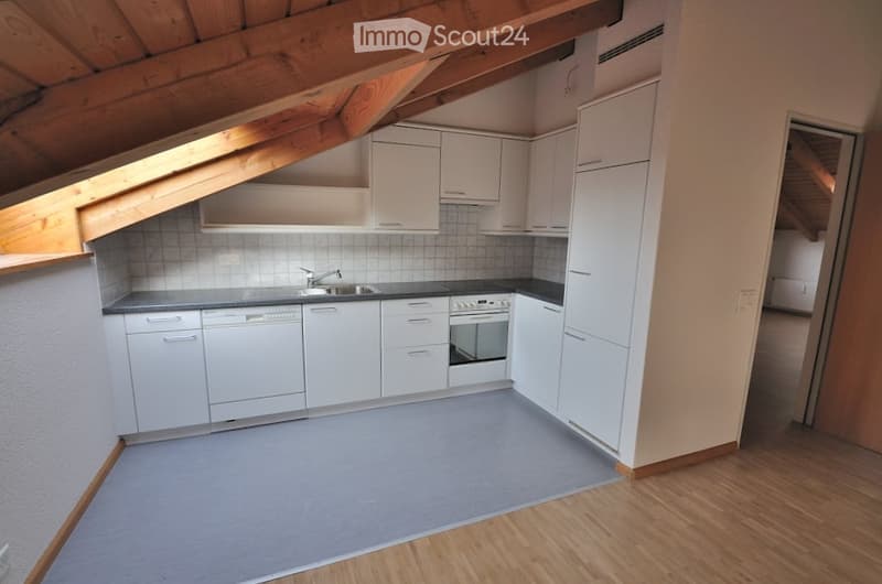 Modern kitchen with white cabinets, a sink, and an oven, featuring wooden beams on the ceiling and wooden flooring.