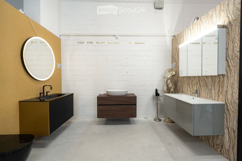 Modern bathroom with white brick walls, a large round mirror, a dark wooden vanity, a white sink, and a sleek bathtub.