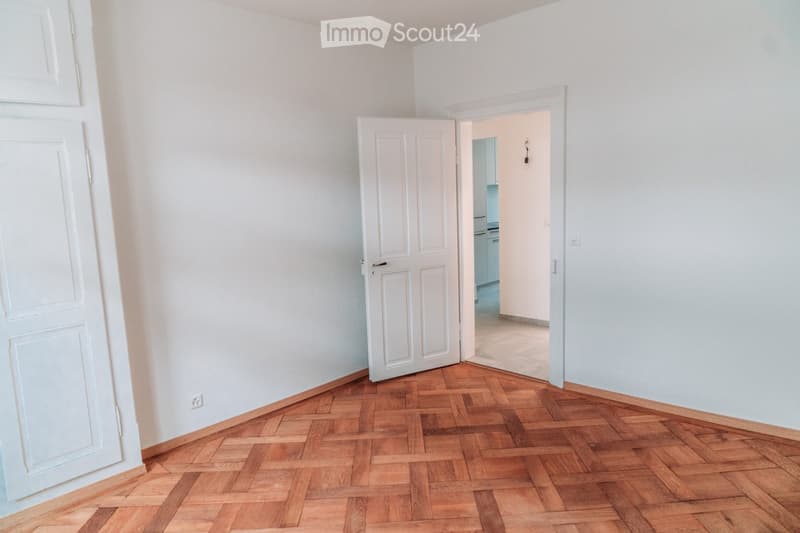 empty room, white walls, wooden parquet floor, open door, light colored tiles