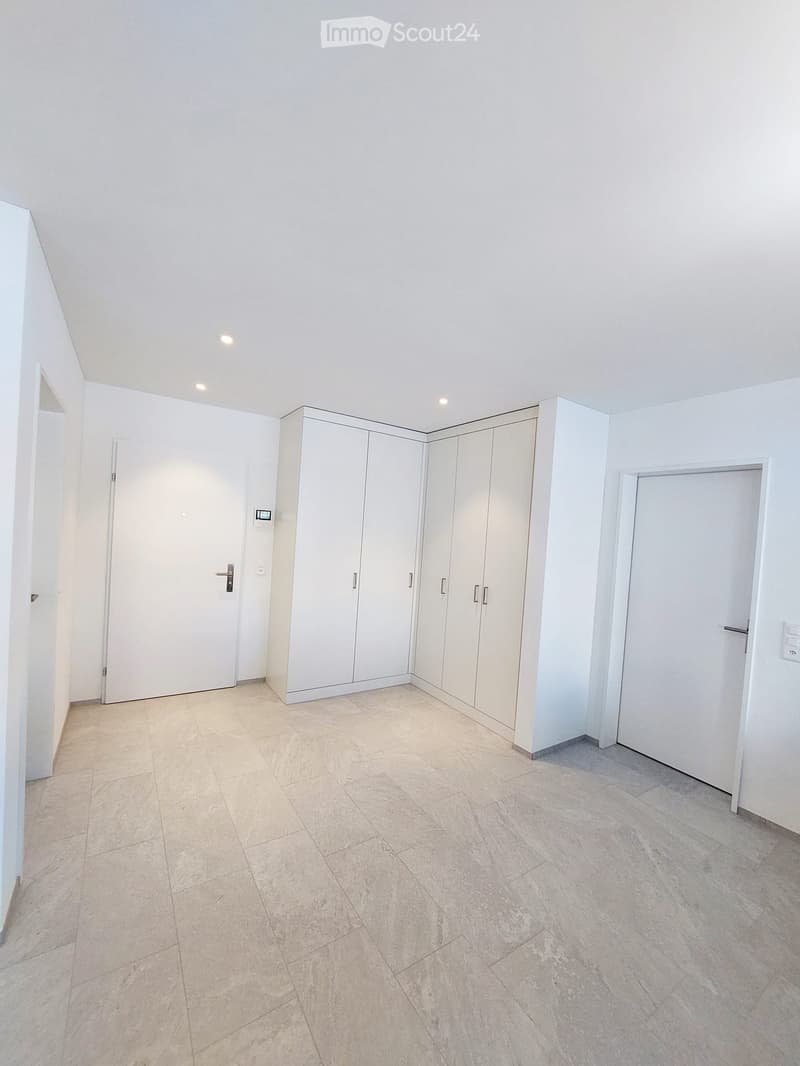Empty room with white walls, tiled floor, built-in white cabinets, and two white doors.
