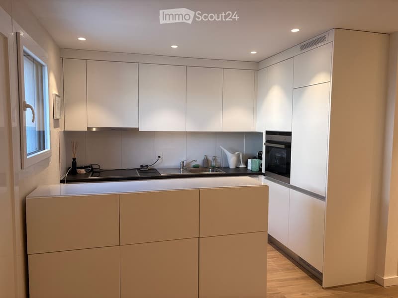 Modern kitchen with white cabinets, a sink, an oven, and various small appliances on the counter.