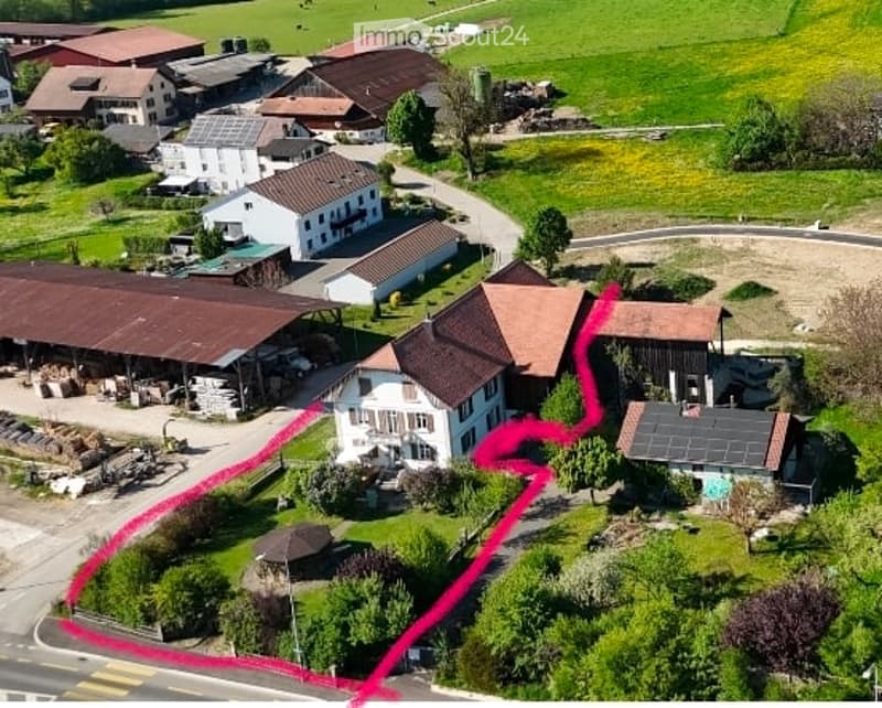 Aerial view of a rural residential area with multiple houses, barns, and open fields. The highlighted area outlines a specific property boundary.