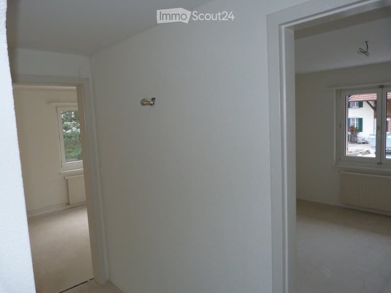 Empty room, white walls, white flooring, radiators, windows with a view outside