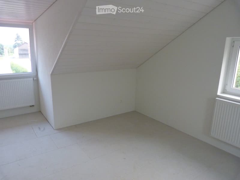 Empty attic room with white walls, white tiled floor, and two windows with wooden frames