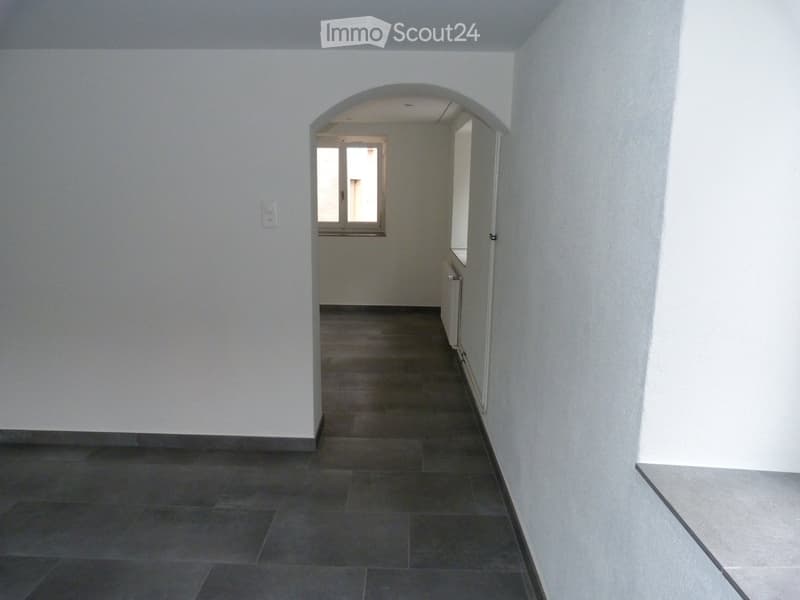 empty room, white walls, dark grey tiled floor, arch opening