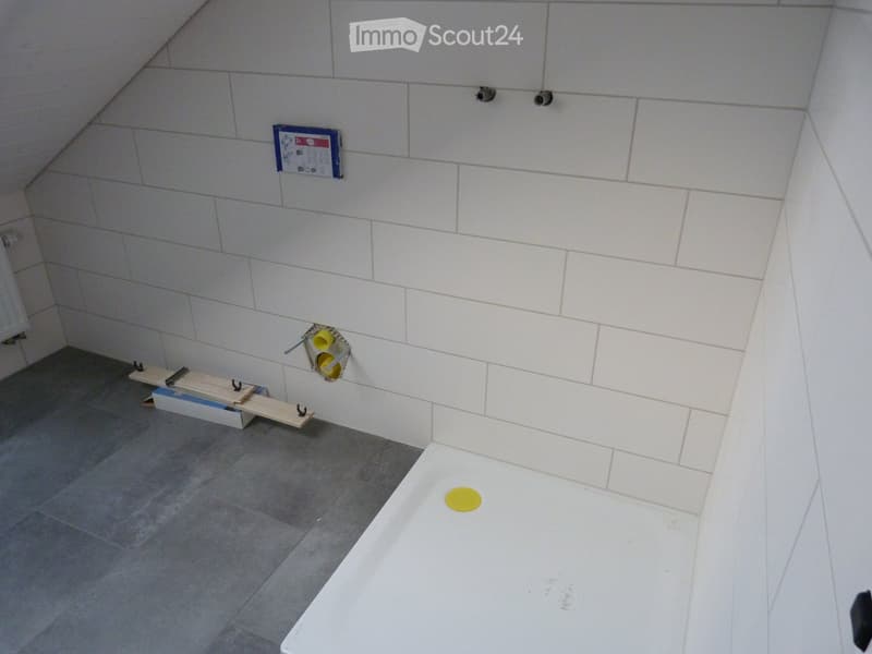 Corner bathroom with tiled walls and floor, empty shower, under construction fixtures and fittings