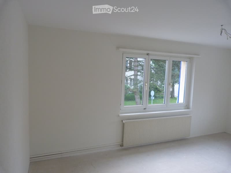 empty room with white walls, radiator, white ceiling, large window