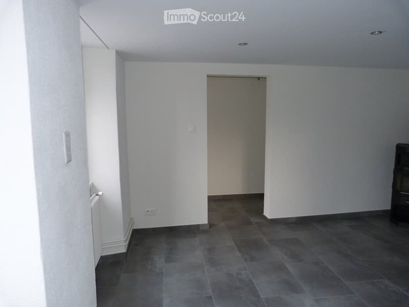 empty room, white walls, gray tile flooring, power outlet, open door leading to another room
