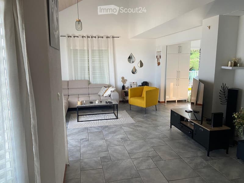 Modern living room with grey sofa, coffee table, yellow armchair, TV stand, and decorative mirrors.