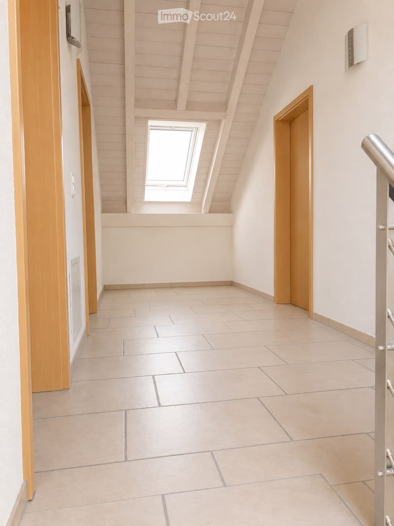 Empty hallway with tiled floor, wooden doors, and a skylight window at the far end.