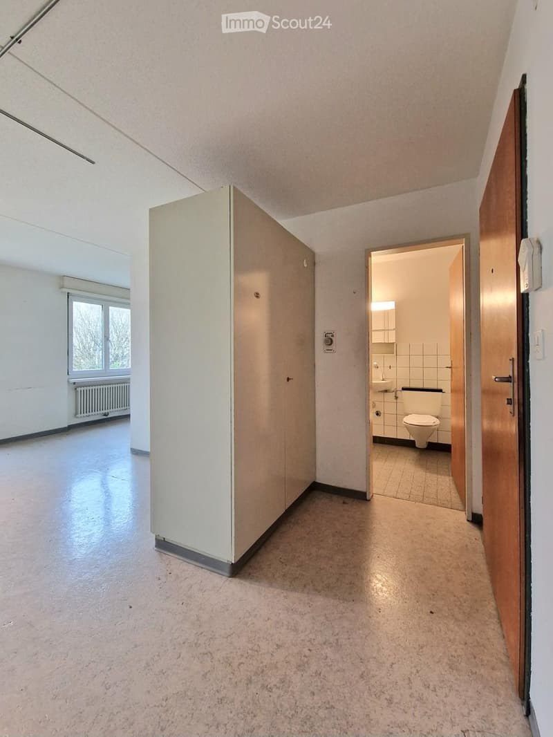 Empty hallway with light-colored walls, carpeted floor, and a partially open door leading to a small bathroom.